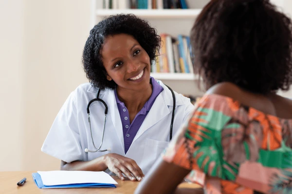 African doctor consulting with patient in medical office